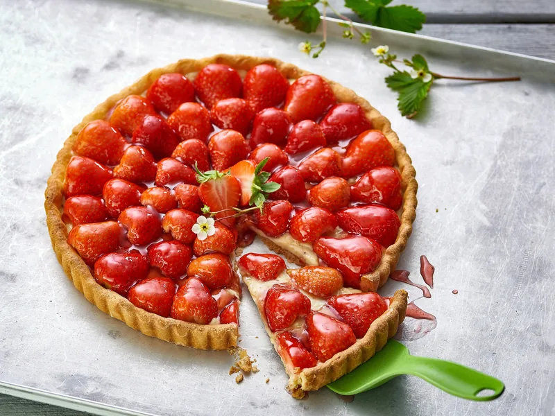 Une tarte aux fraises entière, une part entamée